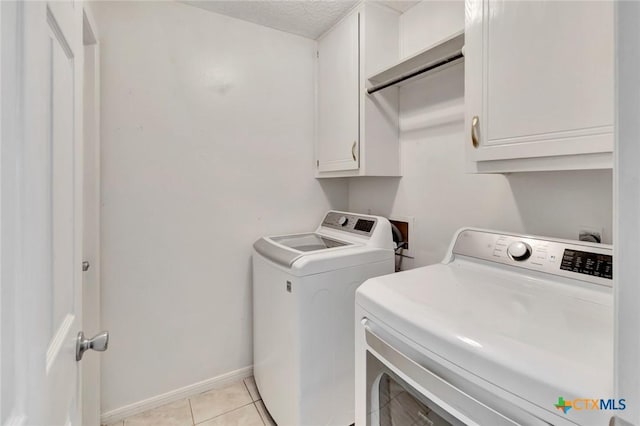 108 Bridle Ln, Victoria, TX 77904 - laundry area with washing machine and dryer, cabinet space, light tile patterned floors, baseboards, and a textured ceiling