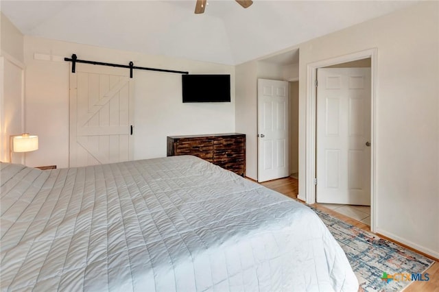 108 Bridle Ln, Victoria, TX 77904 - bedroom with a barn door, lofted ceiling, light wood-style floors, a ceiling fan, and baseboards