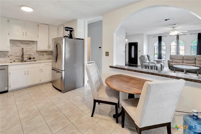 108 Bridle Ln, Victoria, TX 77904 - kitchen featuring appliances with stainless steel finishes, a sink, arched walkways, ceiling fan, and decorative backsplash