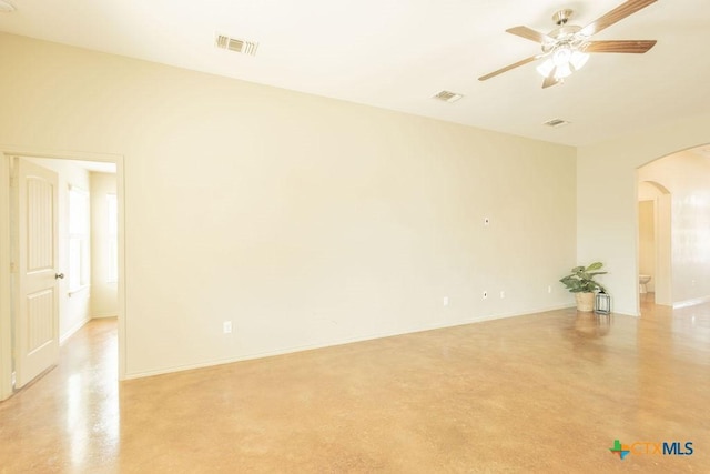 empty room featuring visible vents, concrete floors, arched walkways, and ceiling fan