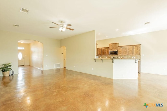 unfurnished living room featuring finished concrete floors, arched walkways, and visible vents