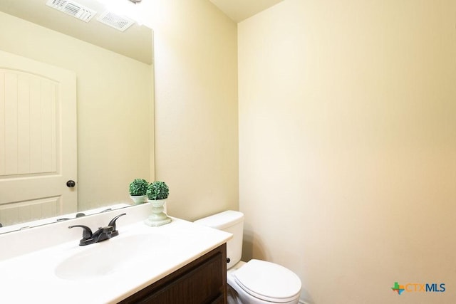 bathroom with visible vents, vanity, and toilet