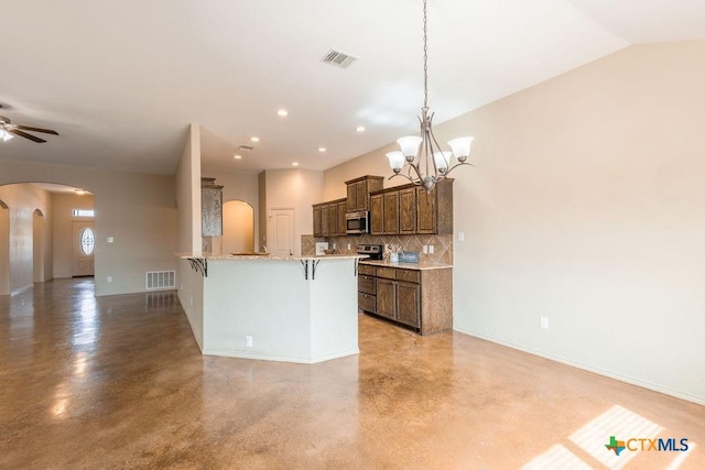 kitchen with arched walkways, stainless steel microwave, visible vents, and a kitchen bar