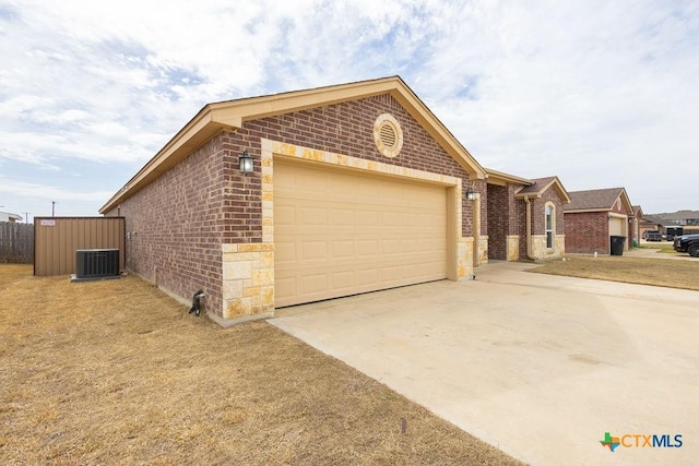 view of front facade featuring a garage, driveway, brick siding, and central AC unit