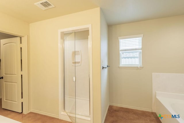 bathroom with a bath, a stall shower, visible vents, and baseboards