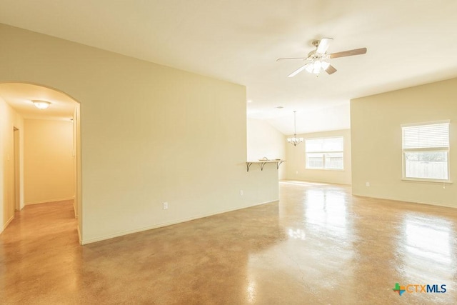 empty room featuring baseboards, arched walkways, vaulted ceiling, concrete flooring, and ceiling fan with notable chandelier