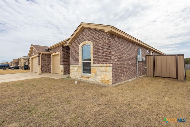 exterior space featuring brick siding, concrete driveway, stone siding, an attached garage, and a front yard