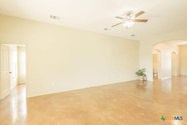 spare room with arched walkways, visible vents, and finished concrete floors