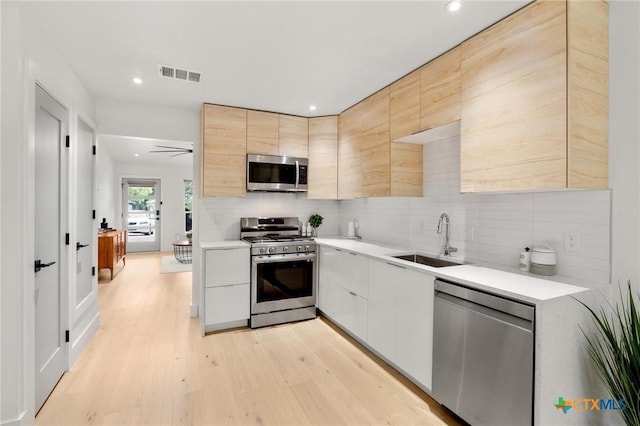 kitchen featuring appliances with stainless steel finishes, a sink, modern cabinets, light countertops, and recessed lighting