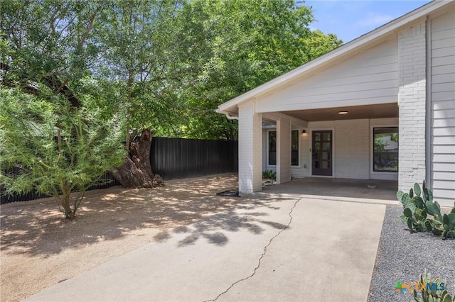 view of patio with fence, driveway, and an attached carport