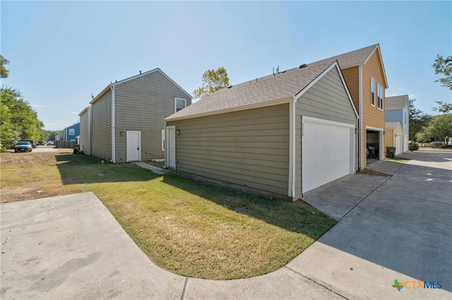 view of side of home featuring roof with shingles, a yard, and driveway