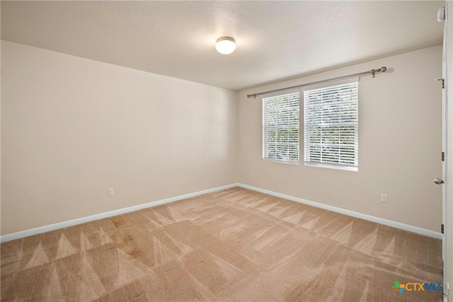 unfurnished room featuring baseboards and light colored carpet