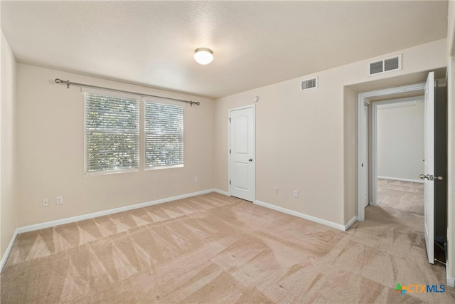 spare room with light carpet, baseboards, and visible vents