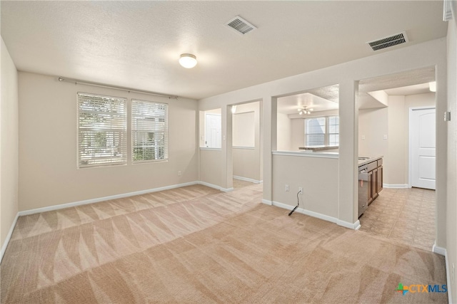 carpeted spare room with a textured ceiling and an inviting chandelier