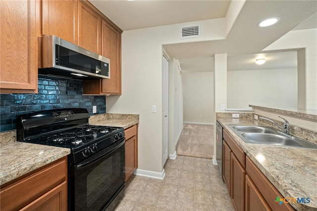 kitchen with light stone counters, stainless steel appliances, backsplash, light tile patterned floors, and sink