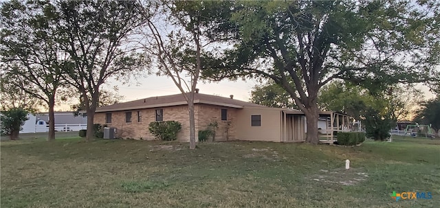 property exterior at dusk with a lawn and cooling unit