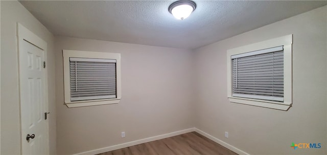 empty room with wood-type flooring and a textured ceiling