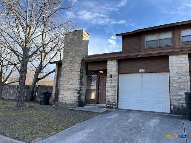 view of front of house featuring driveway, stone siding, a chimney, and fence