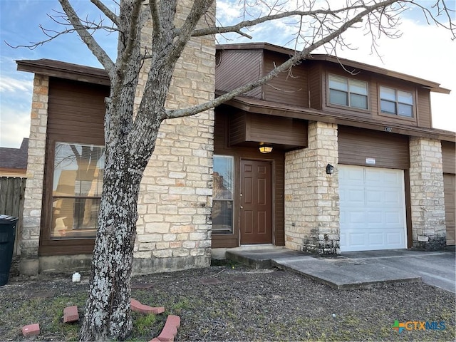 view of front of property with an attached garage, stone siding, driveway, and a chimney