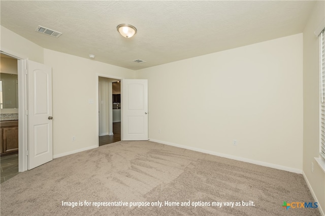 unfurnished bedroom with carpet, a textured ceiling, and ensuite bath