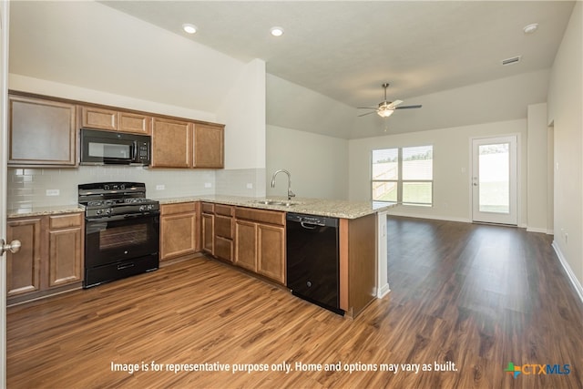 kitchen featuring dark wood-type flooring, lofted ceiling, kitchen peninsula, black appliances, and backsplash