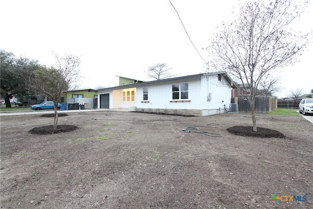 single story home with an attached garage, driveway, and central AC unit