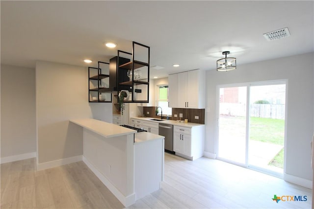 kitchen with light countertops, visible vents, stainless steel dishwasher, white cabinets, and a sink