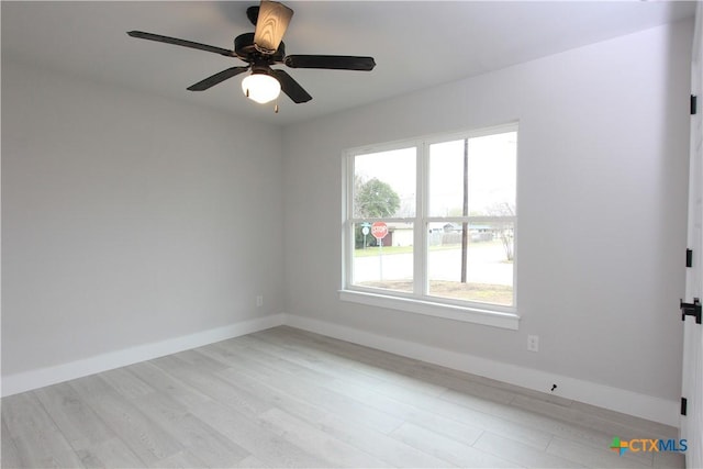 empty room with ceiling fan, light wood-style flooring, and baseboards