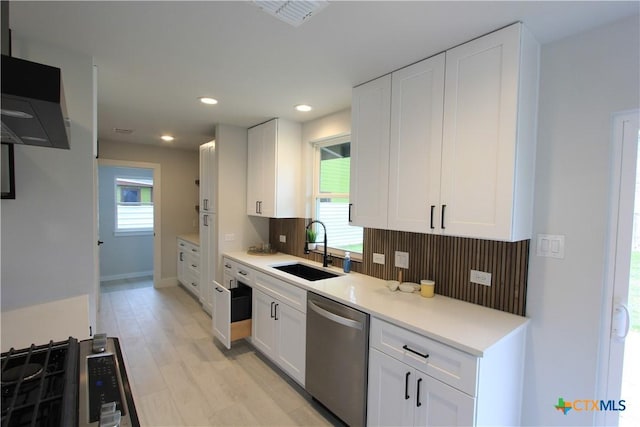 kitchen featuring white cabinets, a sink, light countertops, stainless steel dishwasher, and recessed lighting