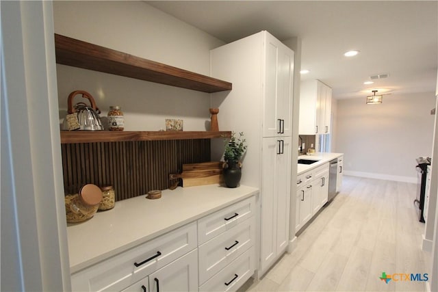 bar with light wood finished floors, baseboards, stainless steel dishwasher, a sink, and recessed lighting