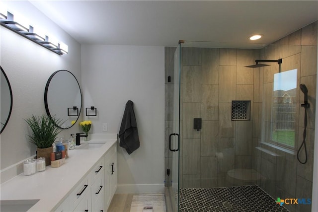 full bathroom with double vanity, a stall shower, baseboards, a sink, and recessed lighting