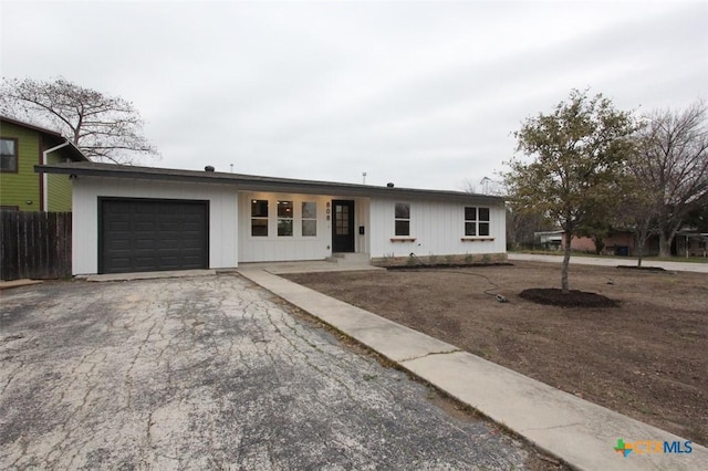 ranch-style house featuring a garage, driveway, and fence