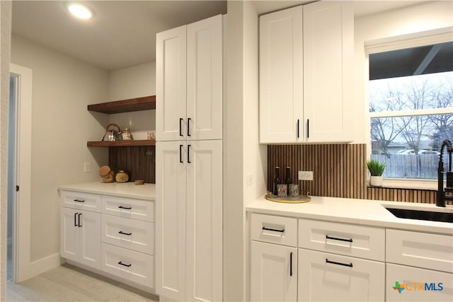 interior space featuring a sink, backsplash, and baseboards