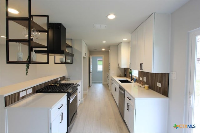 kitchen featuring a sink, gas range, white cabinets, and light countertops