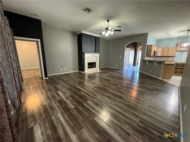 unfurnished living room featuring ceiling fan, dark hardwood / wood-style flooring, and sink