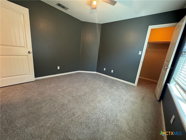 unfurnished bedroom with carpet flooring, ceiling fan, and a spacious closet