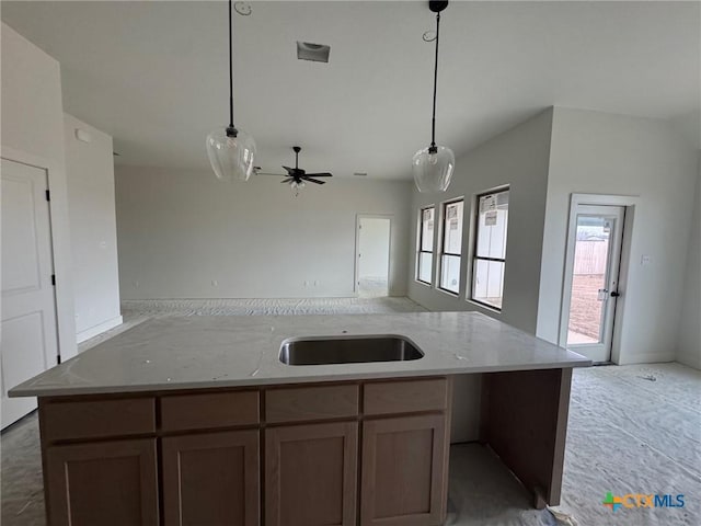 kitchen featuring an island with sink, open floor plan, a sink, and hanging light fixtures