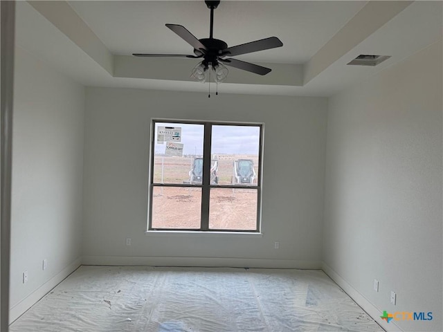 empty room featuring baseboards, a raised ceiling, visible vents, and a ceiling fan