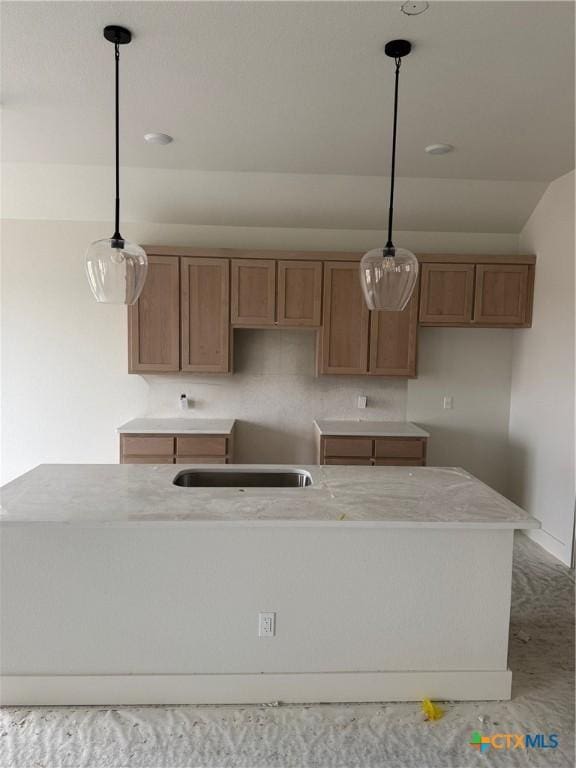 kitchen featuring brown cabinets, decorative light fixtures, and a sink