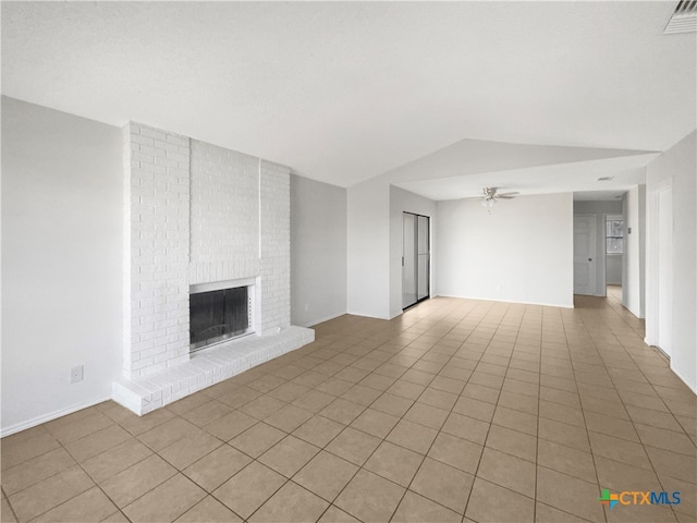 unfurnished living room with ceiling fan, light tile patterned flooring, lofted ceiling, and a brick fireplace