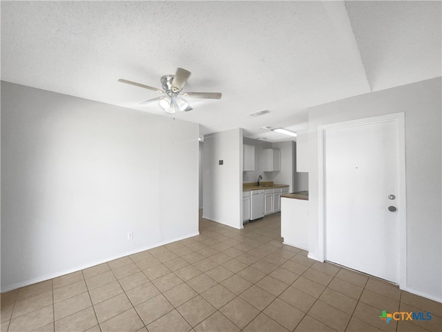 unfurnished living room with tile patterned flooring, ceiling fan, sink, and a textured ceiling