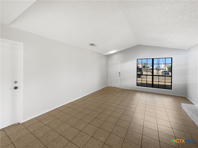 spare room featuring tile patterned floors, a textured ceiling, and vaulted ceiling