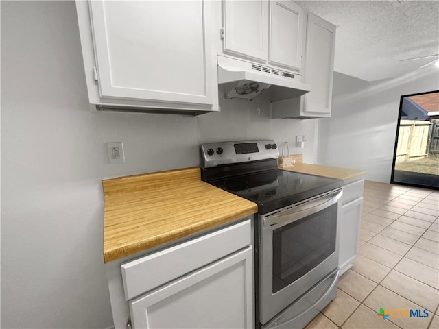 kitchen featuring a textured ceiling, light tile patterned floors, white cabinets, and stainless steel electric range