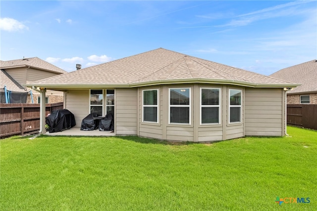rear view of house with a lawn, a patio, and fence