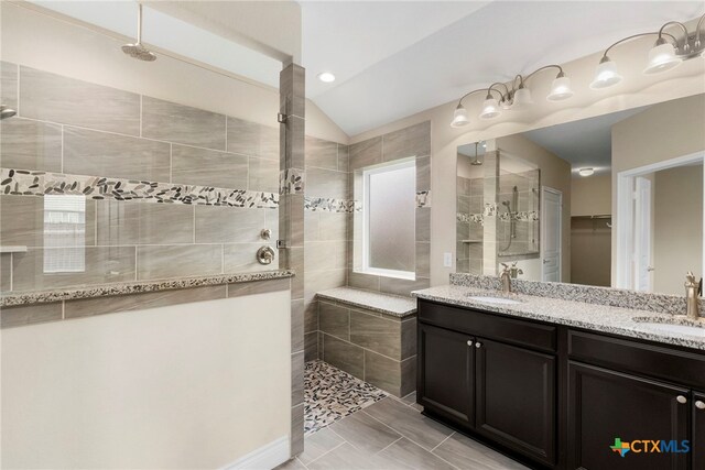 bathroom with a walk in shower, double vanity, and a sink