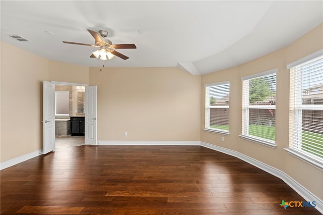 unfurnished room with a ceiling fan, visible vents, dark wood-style flooring, and baseboards