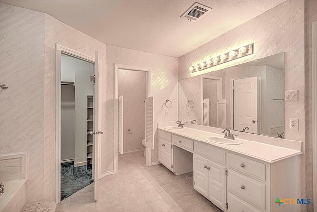 bathroom with tile patterned floors, vanity, a textured ceiling, and toilet