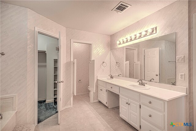 bathroom featuring tile patterned floors, vanity, toilet, and a textured ceiling