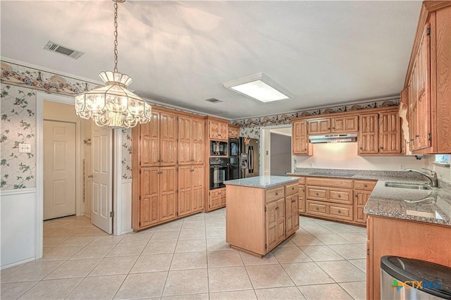 kitchen featuring a center island, sink, light stone counters, a notable chandelier, and black appliances