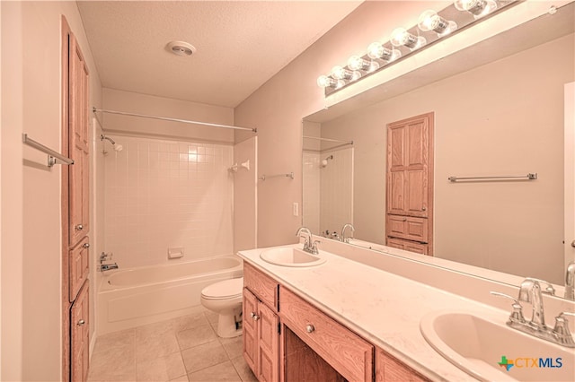 full bathroom with tile patterned floors, a textured ceiling, toilet, vanity, and tiled shower / bath